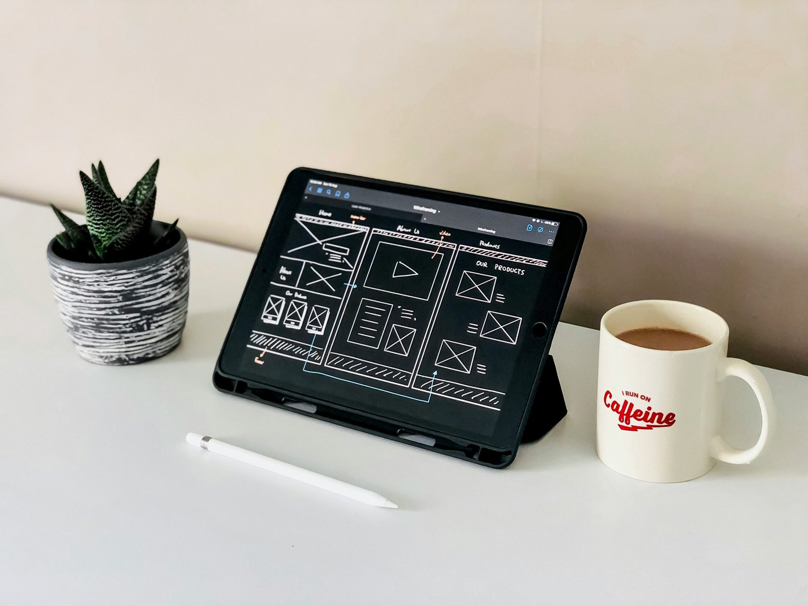 black ipad beside white ceramic mug on white table